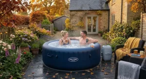A couple relaxing with warm drinks in a 4 person inflatable hot tub during autumn.